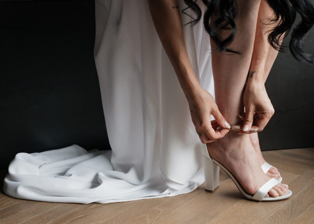 bride putting on shoes ad wedding dress